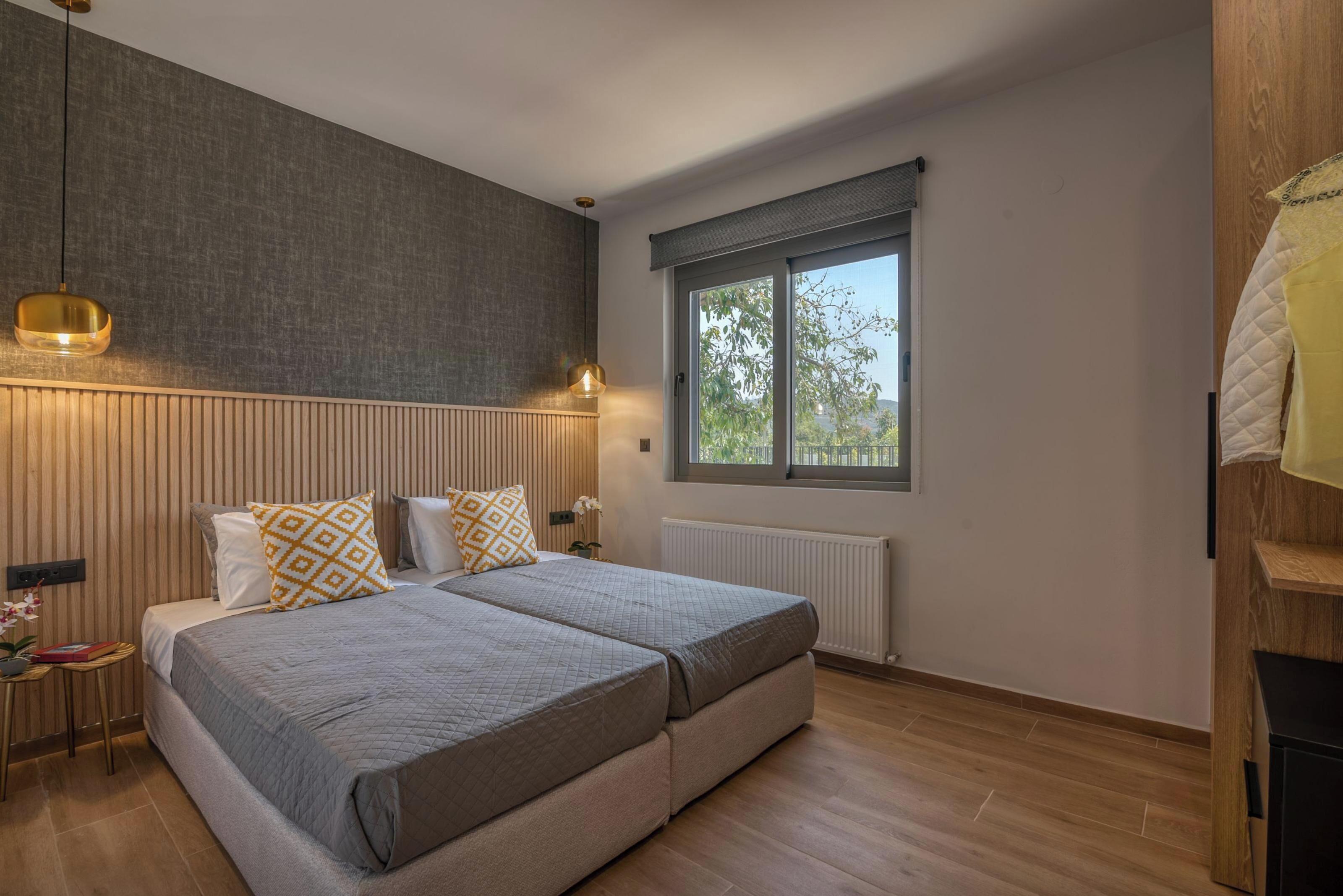 A bedroom with two beds, a large window, and a radiator.
