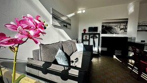 A modern living room with a sofa, a glass coffee table, and a potted orchid. - 700m from the sea, apartment with terrace, parking and pétanque court. (Cayeux-sur-Mer)