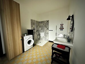 Une petite salle de bain équipée d’un lave-linge, de toilettes et d’un lavabo.