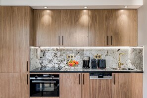 A modern kitchen with wooden cabinets, a marble backsplash, and built-in appliances including a Siemens dishwasher and oven. - Merveil - Luxury Suite - Champs Elysees - St Cyr I (Paris)