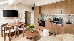 Een moderne keuken met houten kastjes, een marmeren aanrechtblad en een eethoek met een ronde tafel en stoelen.
