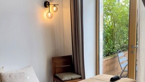 A bedroom with a bed, a bedside table, a chair, and a window with curtains. - Five & You (Josse)