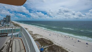 Ein Strand mit einem gewundenen Gehweg mit Blick auf den Ozean, feinem Sand und Gebäuden im Hintergrund.