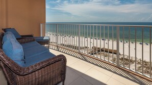 A balcony with wicker furniture overlooking a beach.