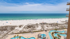 A beach resort with a pool area, beach umbrellas, and a clear view of the ocean.