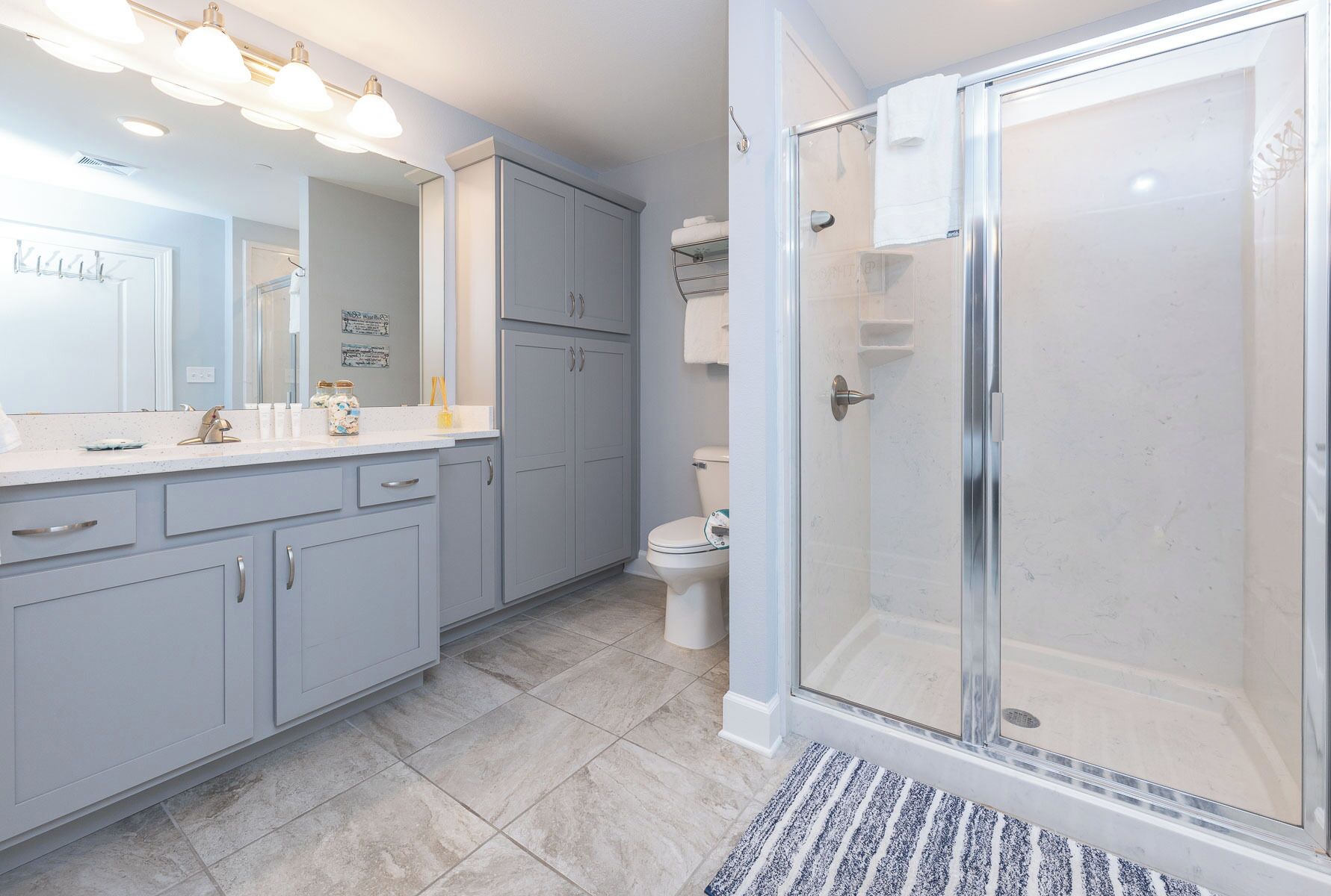 Une salle de bain moderne équipée d’une douche, de toilettes et d’un meuble-lavabo avec des placards et un miroir.