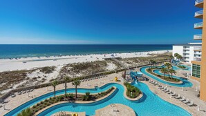 Een resort met een groot zwembad, een strand en een glijbaan.