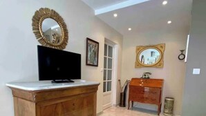 Una habitación con tocador de madera, televisor, espejo y lavamanos.