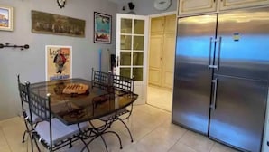 Una cocina con mesa de vidrio, refrigerador de acero inoxidable y decoración en la pared.