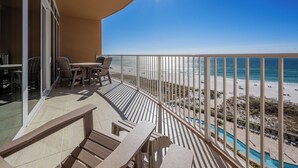 A balcony with a view of the beach and pool.