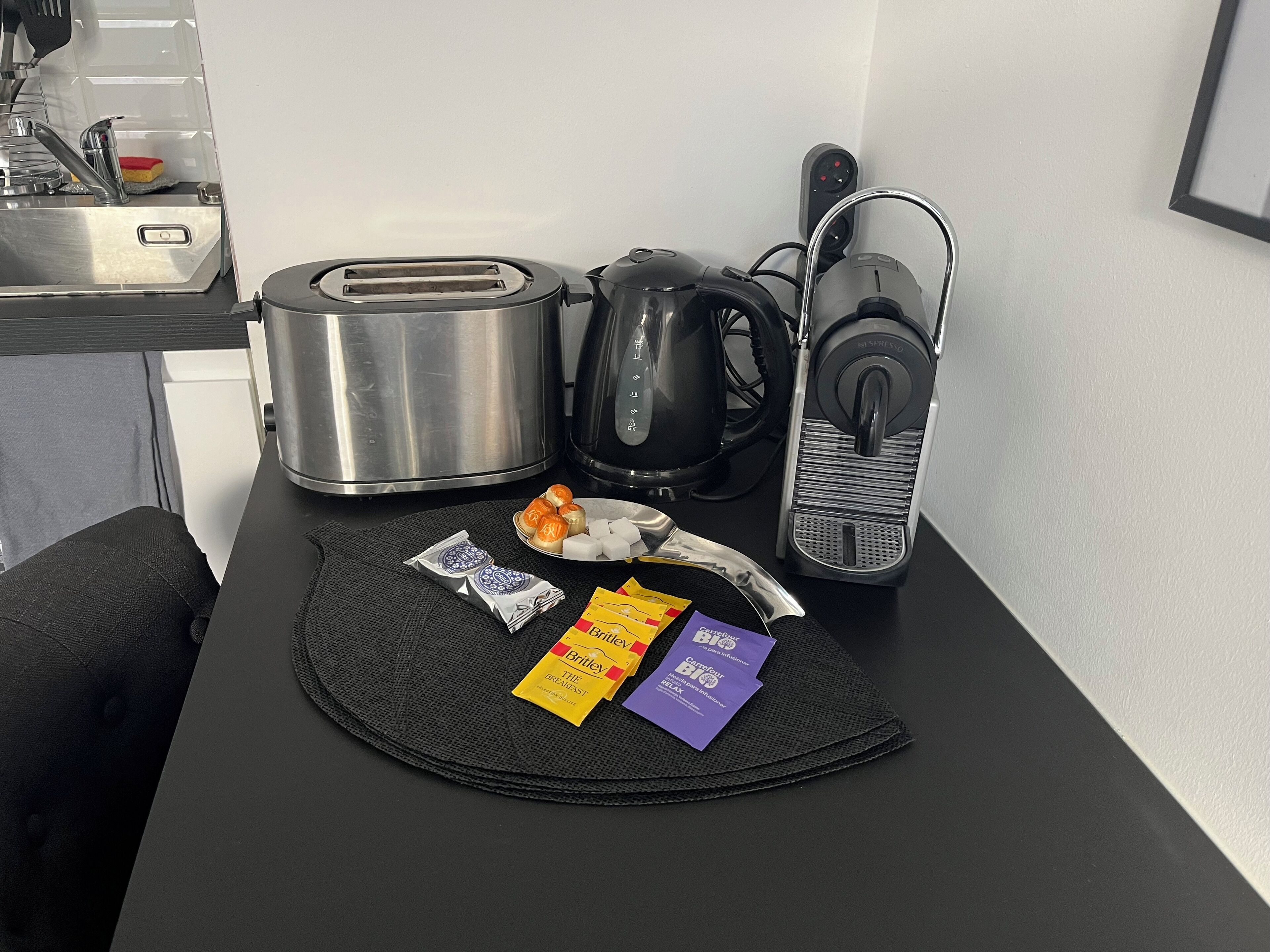 Ett litet kök med en brödrost, vattenkokare och kaffebryggare på en bänkskiva.