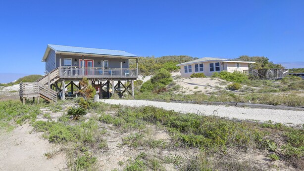 Propiedad frente a la playa con una casa de dos pisos, balcón y una construcción separada.