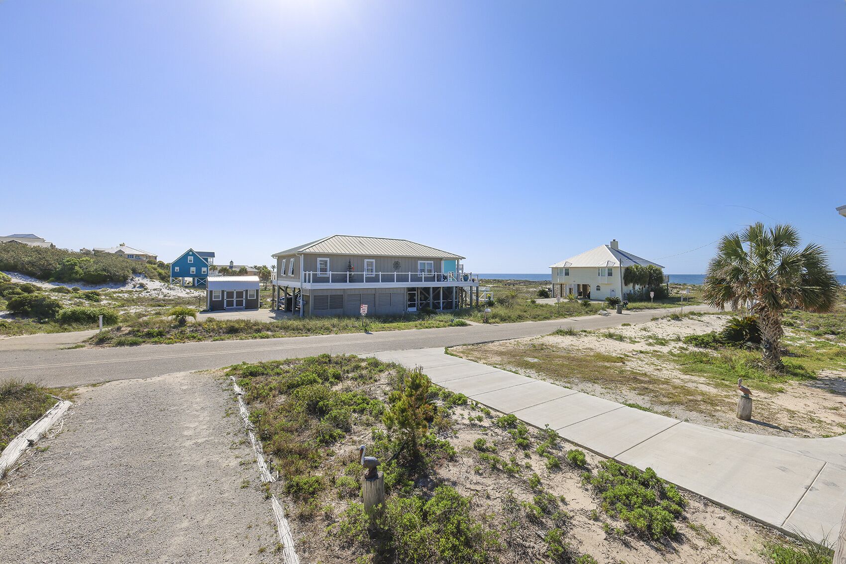 Una propiedad costera con una casa grande, un edificio más pequeño y vista a la playa.