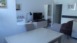 Cocina compacta con comedor, televisor de pantalla plana y estantería empotrada.
