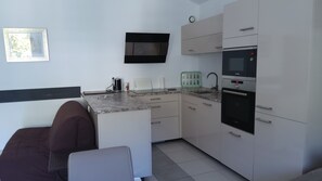 Una cocina moderna con microondas, horno y cafetera integrados en la encimera.