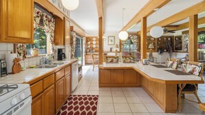 Una cocina amplia con armarios de madera, una isla central y una zona de comedor con sillas estampadas de flores.