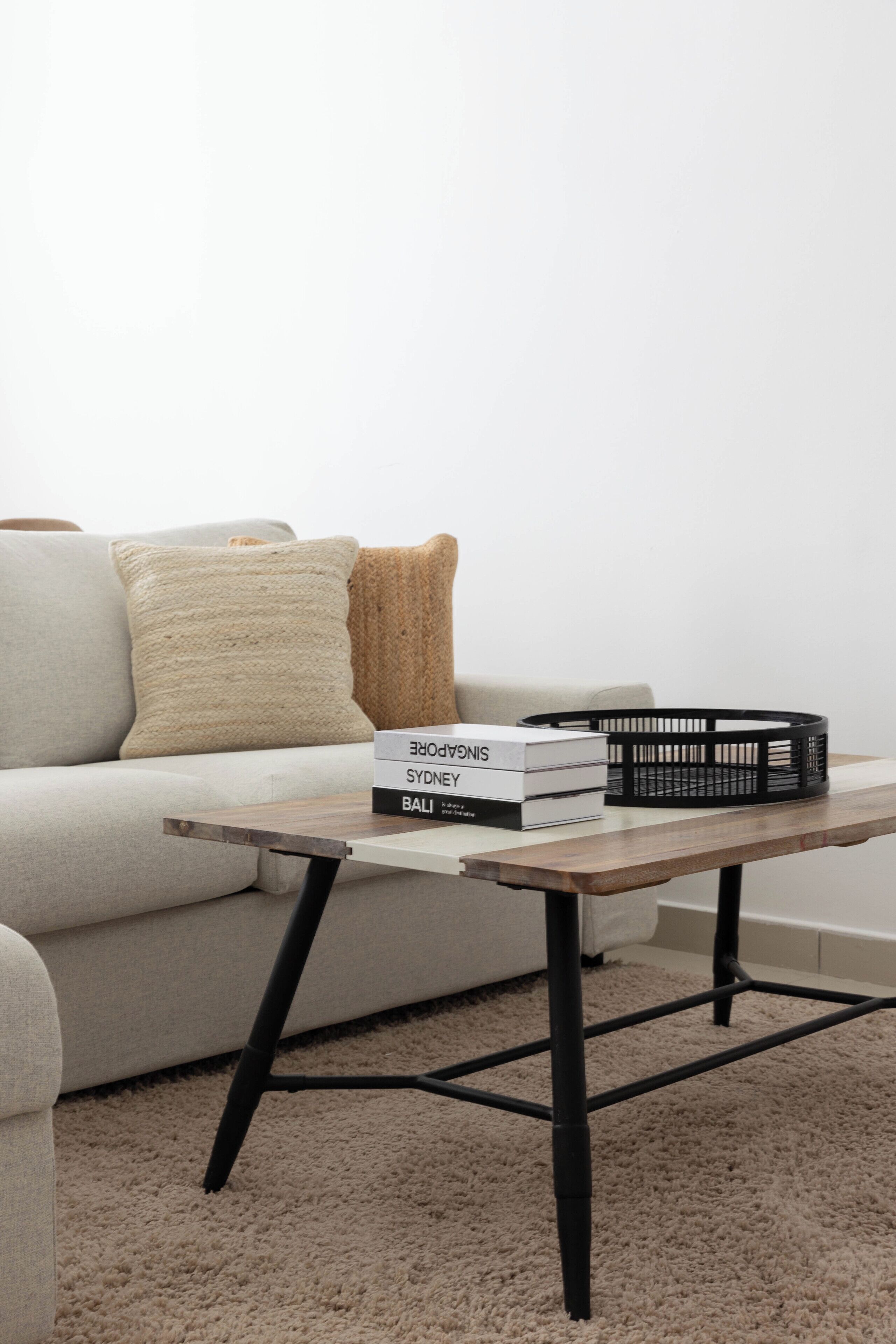 A modern living room with a light-colored sofa, a wooden coffee table, and a few books.
