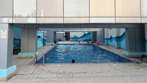 A swimming pool area with a tiled floor, a diving board, and a lifebuoy. - Handsome 1BR in Armada Tower 3 (Dubai)