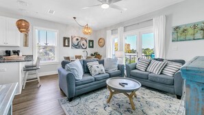Un salon moderne avec un canapé gris, une table basse et un tapis à motifs.