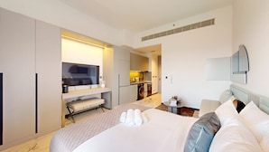 A hotel room with a bed, a TV, a kitchenette, and a bathroom. - Meydan Studio | Skyline View, 12 Mins to Downtown I Mag Eye 910 (Meydan)