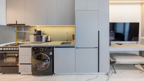 A modern kitchen with a built-in washing machine, a stove, a microwave, and a refrigerator.