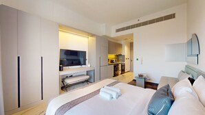 A modern hotel room with a large bed, a TV, a small kitchen area, and a bathroom. - Mag Eye 920 - Classy Studio Apartment in Meydan (Meydan)
