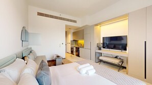 Ein Hotelzimmer mit Bett, Schreibtisch, Fernseher und einer Küchenzeile.