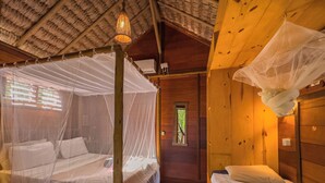 A room with two beds, each with a canopy, wooden walls, and a thatched roof. - Pousada Castelo do Vento (Cruz)