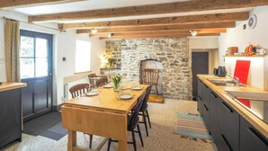 A rustic kitchen with a stone wall, wooden beams, and a built-in oven.