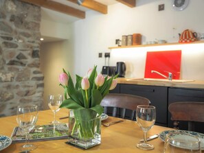 Una mesa de comedor con un jarrón de tulipanes, copas de vino y una revista.