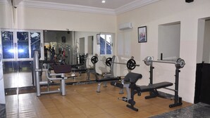 Een sportschool met diverse fitnessapparaten, waaronder een bankdrukpers, een squatrek en losse gewichten.