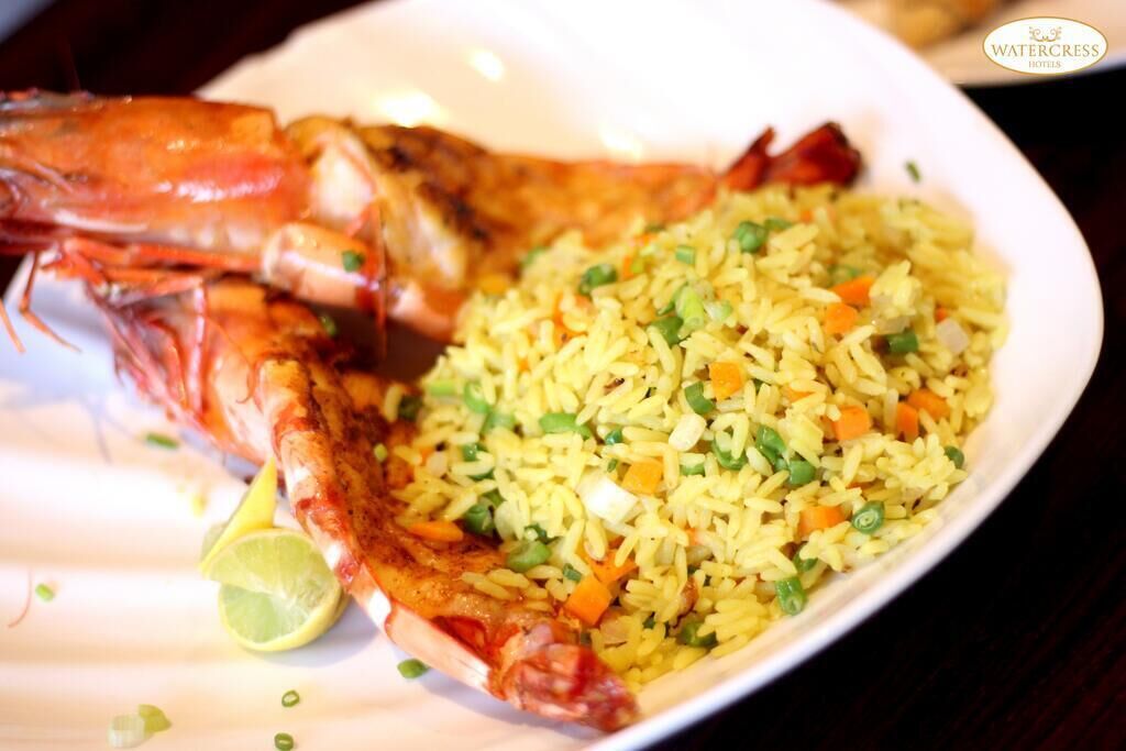 A plate of fried rice with vegetables and a whole cooked lobster.