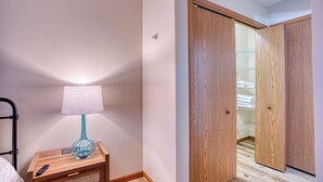 A bedroom with a wooden nightstand, a lamp, a bed, and a closet with a wooden door. - Retro '90s 2BR/2BA • Private Entrance • Pet-Friendly • King Bed • 5 M... (Newburgh)
