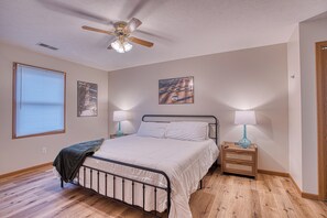 A bedroom with a bed, two bedside tables with lamps, a ceiling fan, a window with blinds, and two wall-mounted pictures. - Retro '90s 2BR/2BA • Private Entrance • Pet-Friendly • King Bed • 5 M... (Newburgh)