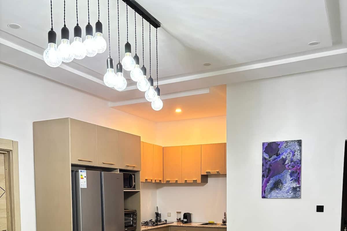 A modern living room with a grey sofa, a coffee table, and a kitchen area with cabinets and appliances.