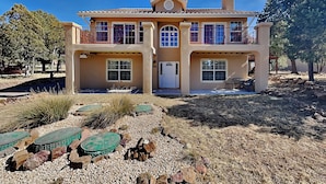 A two-story house with a flat roof, a central entrance, and a covered patio area.