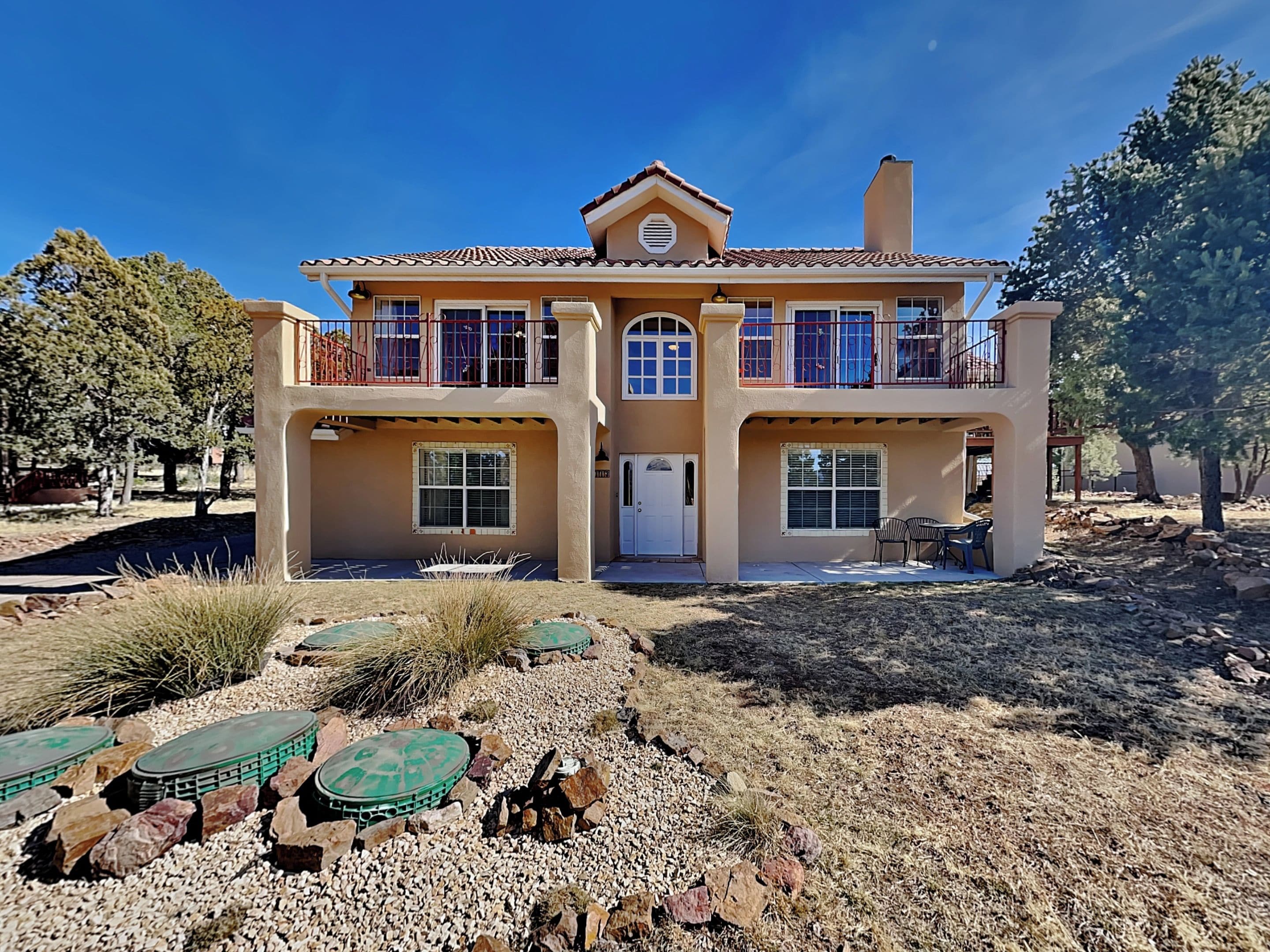 A two-story house with a flat roof, a central entrance, and a covered patio area.