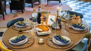 A round dining table set with plates, glasses, and a bottle, surrounded by chairs. - RKD SUITES Asaba (Asaba)