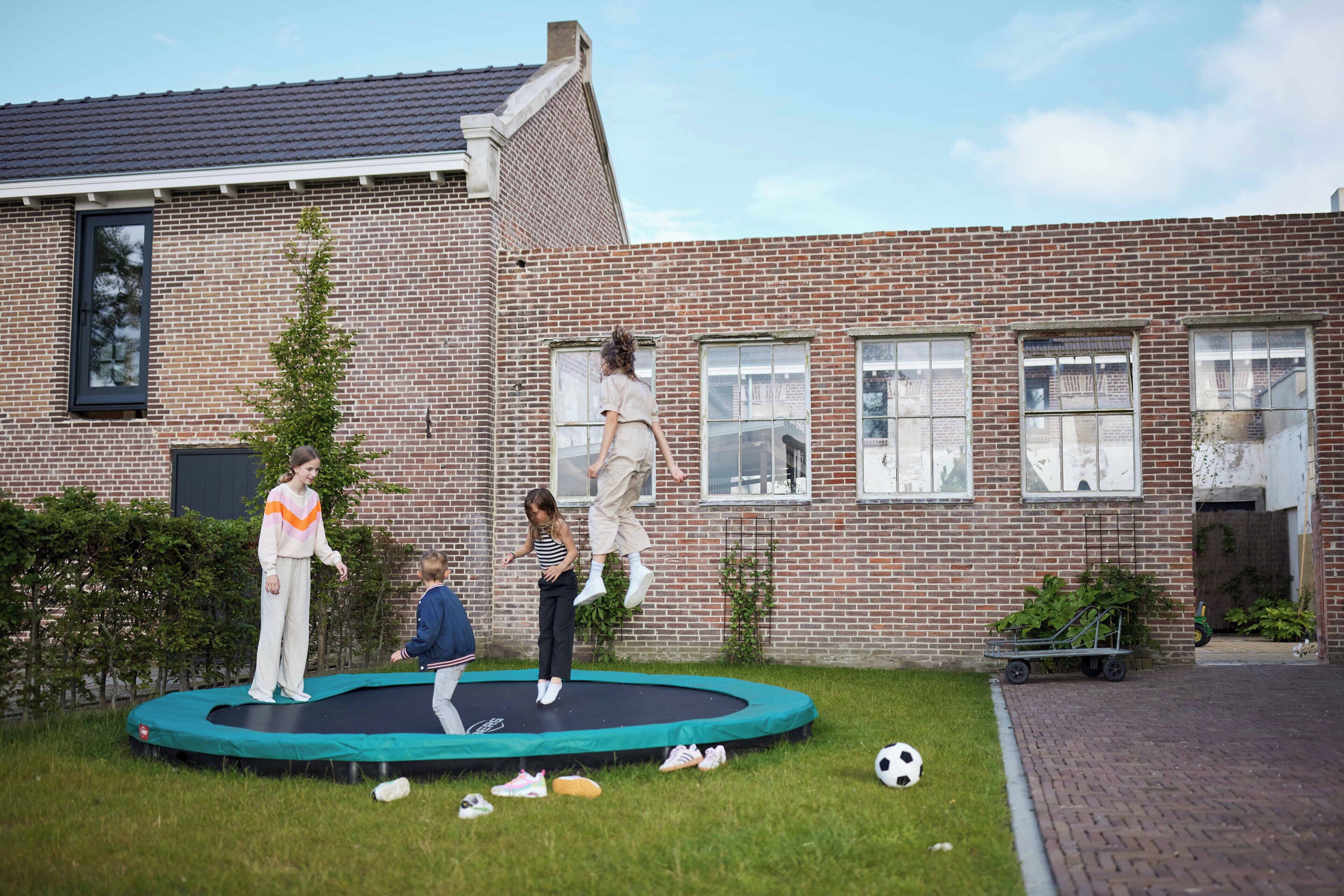 A brick building with a green trampoline in front.