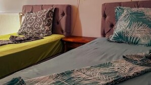 Una habitación con dos camas, cada una con un edredón de estampado diferente. Hay lámparas de pared a cada lado de las camas.