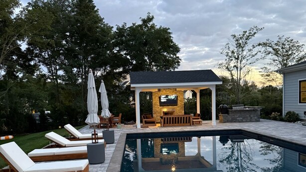 A swimming pool with lounge chairs and a covered seating area.
