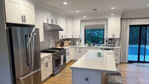 A modern kitchen with stainless steel appliances, white cabinetry, and a large island.