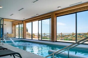 Una piscina cubierta con vista a una terraza de madera y una barandilla.