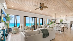 A spacious living area with a large sofa, a dining table, and a kitchen area. - Stay Blessed Villa - Always Sandy Beach - Walkable To Restaurant By Beach! (Farmer's Hill)