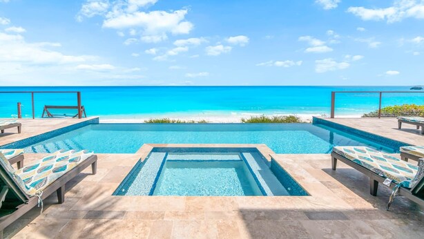 A infinity pool with lounge chairs and a view of the ocean. - Stay Blessed Villa - Always Sandy Beach - Walkable To Restaurant By Beach! (Farmer's Hill)