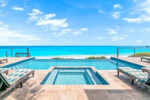 A infinity pool with lounge chairs and a view of the ocean. - Stay Blessed Villa - Always Sandy Beach - Walkable To Restaurant By Beach! (Farmer's Hill)