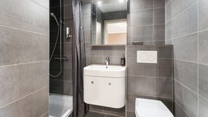 Un baño moderno con ducha, inodoro y lavamanos.