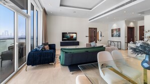 Una sala de estar moderna con un televisor grande, asientos cómodos y un balcón con vistas a la ciudad.