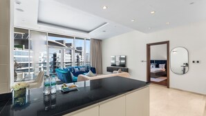 Una habitación de hotel moderna con un ventanal grande, una encimera negra, un sofá, una cama y un espejo.