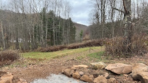 A natural outdoor setting with a gravel path, large rocks, and leaf-covered ground. - The Cozy Cabin: Mountain Escape at Snowshoe, WV (Slaty Fork)
